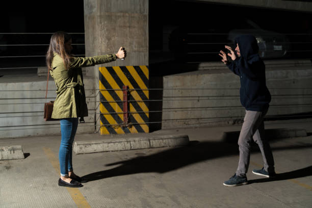 bandido levantando los brazos frente a la víctima en el callejón - pulverizador de pimienta fotografías e imágenes de stock