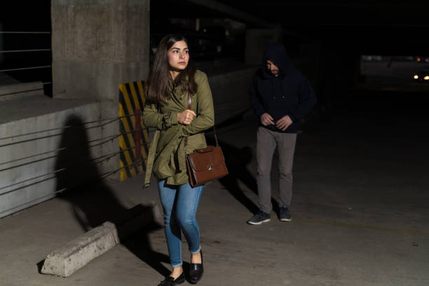 istock Criminal Walking Behind Unsuspecting Young Woman In Dark 1207365356