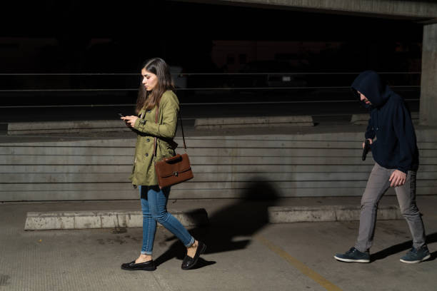 istock Criminal Walking Behind Unsuspecting Woman 1207365984