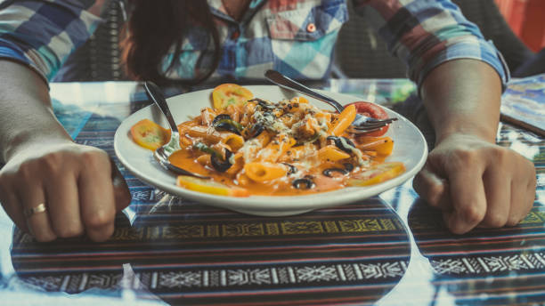 istock Delicious pasta with tomato sauce. Silverware placed on plate of palatable pasta with tomato sauce and olives on ornamental table in cafeteria 1207366001