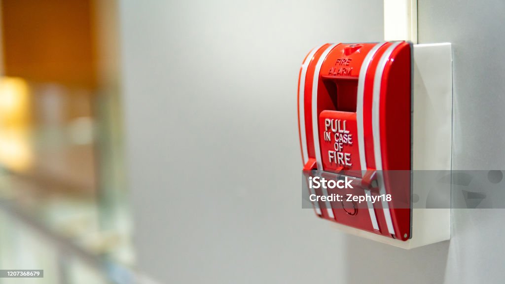 Fire alarm switch on the wall Red fire alarm switch on concrete wall in office building. Industrial fire warning system equipment for emergency. Fire Alarm Stock Photo