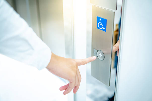 main mâle appuyant sur le bouton vers le haut de l’ascenseur handicapé - elevator push button stainless steel floor photos et images de collection