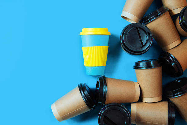 istock zero waste concept.Stylish reusable eco coffee cup and multiple single use cardboard cups. ban single use plastic. Sustainable lifestyle, flat layout on blue background. 1207368702