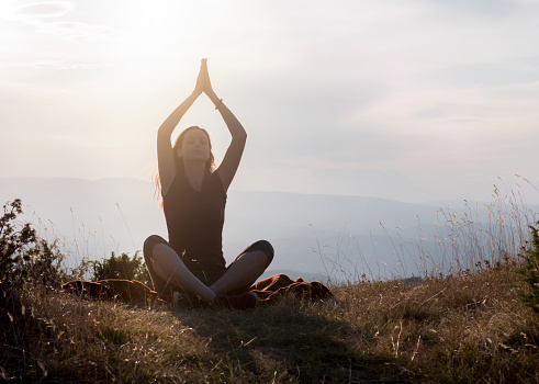 Healthy young woman practicing yoga in nature at sunrise