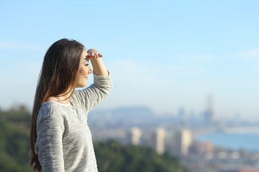 Woman looking away protecting sight with hand