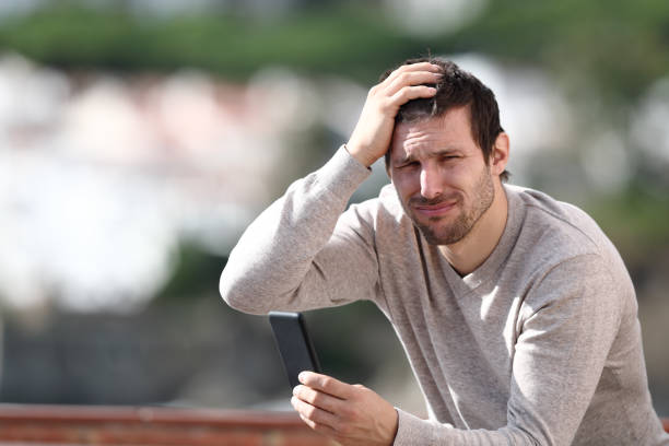 istock Confused man holding mobile phone complaining after mistake 1207374902
