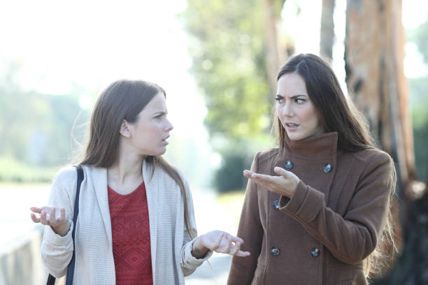 deux femmes fâchés se disputant dans un stationnement en hiver - conflict face to face child arguing photos et images de collection