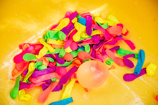 Multicolored Filled and Empty Water Bombs in Yellow Container
