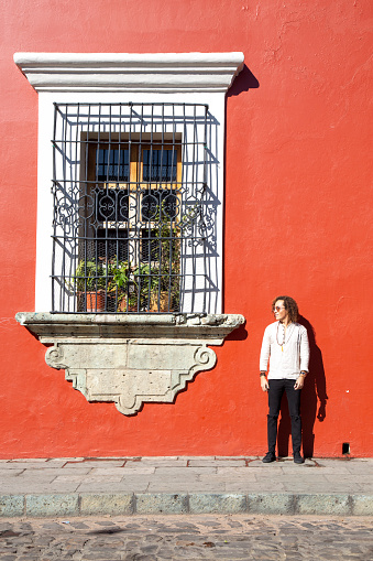 Man standing next to a big window of a red colonial building in Mexico in Mexico, Oaxaca, Oaxaca