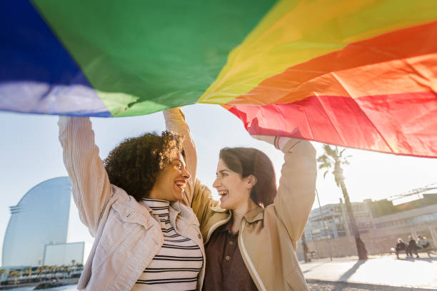 istock two gay girls laughing with rainbow flag 1207385949