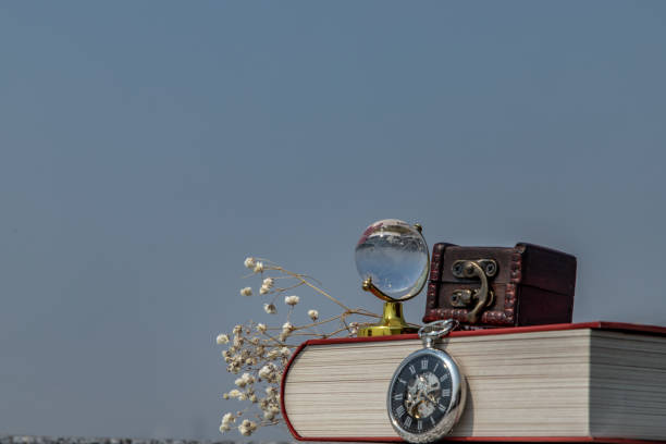 Journey and Learning concept background. crystal globe, pocket watch and stack of books with a sky background.