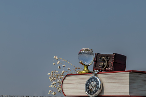 Journey and Learning concept background. crystal globe, pocket watch and stack of books with a sky background. Copy space.