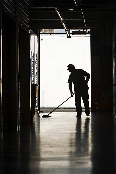 Silhouette of man moping floor Silhouette of a man moping warehouse floor custodian silhouette stock pictures, royalty-free photos & images