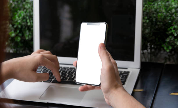 istock Woman holding a modern smartphone with blank white screen and a laptop 1207390822