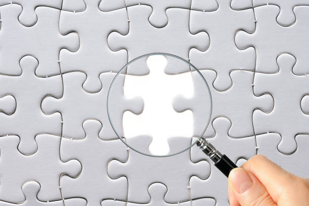 istock Search for missing last puzzle piece with magnifying glass 1207392195