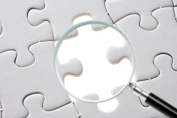 istock Search for missing last puzzle piece with magnifying glass 1207392196