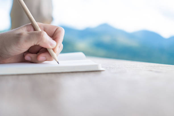 istock Woman hand writing down in small white memo notebook for take a note not to forget or to do list plan for future. 1207404430