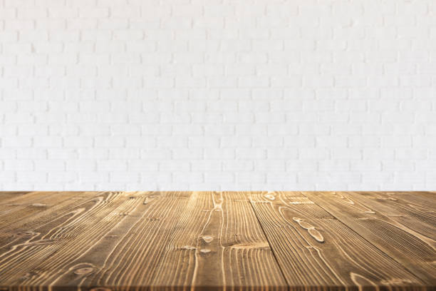 istock Empty wooden board or table with abstract blurred white brick wall background 1207405955