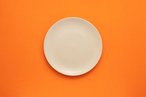 istock Top view empty white ceramic dish on the middle of orange 1207412777
