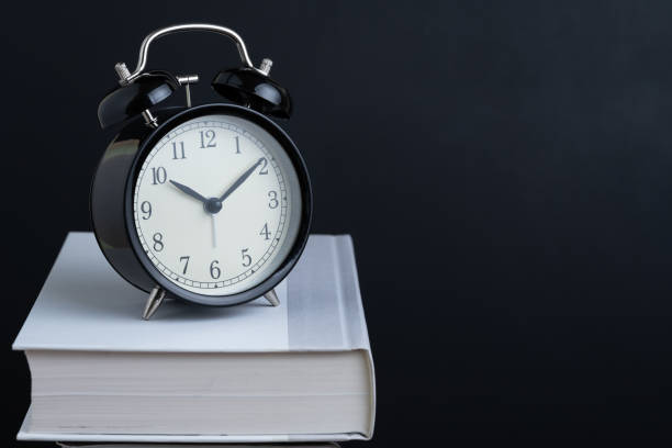 istock Time for reading, concentration in study or educational concept, black retro alarm clock on textbook with chalkboard or blackboard background with copy space 1207414509