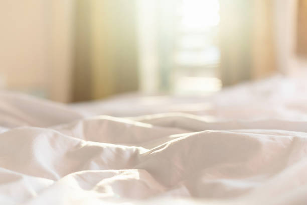 istock White bedding sheets and pillow in hotel room at morning time with sunlight from windows 1207415529