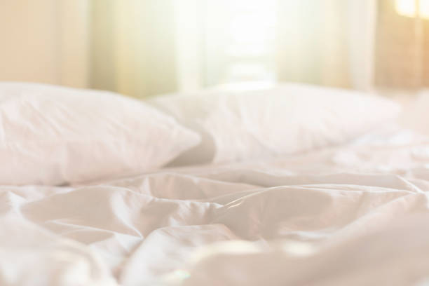 istock White bedding sheets and pillow in hotel room at morning time with sunlight from windows 1207416005