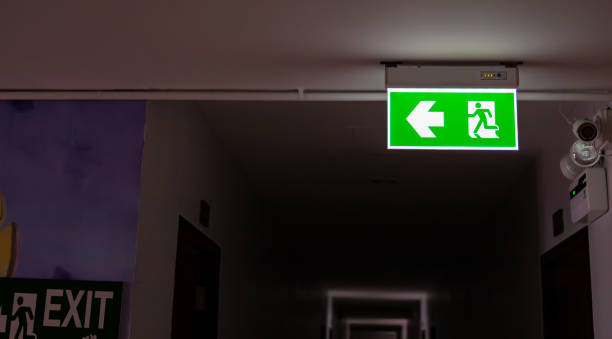 istock Emergency exit green sign hanging by the ceiling inside a hotel alley 1207419693