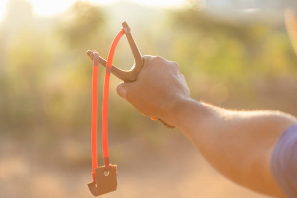 Child playing with a slingshot outdoors, aiming and having fun