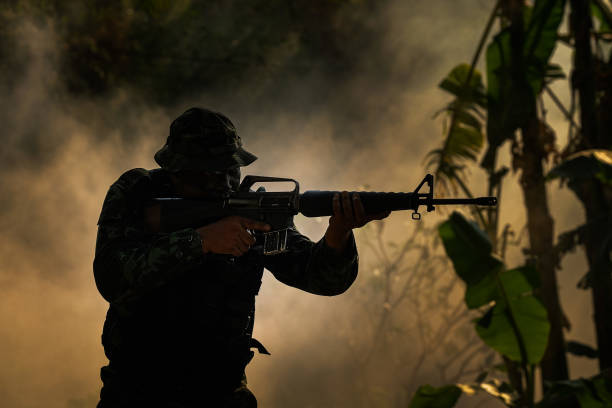 Battlefield with a soldier, armored vehicle and flying helicopters at sunrise