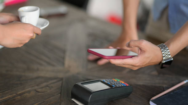 istock Cropped shot of customer using mobile payment in coffee shop 1207432902