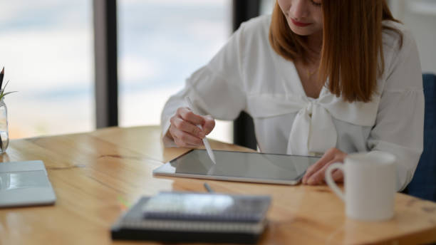 istock Close up view of freelancer drawing on digital tablet with stylus and coffee cup 1207433056