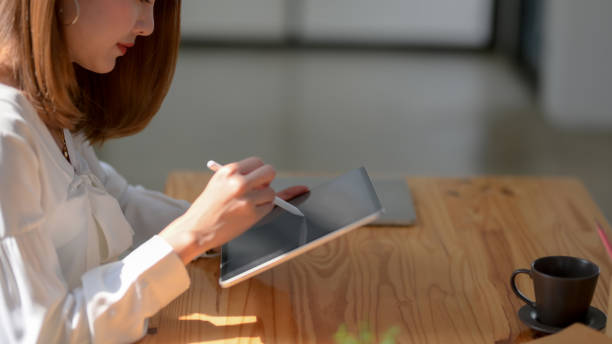 istock Side view of freelancer working on digital tablet with stylus and coffee cup 1207433143