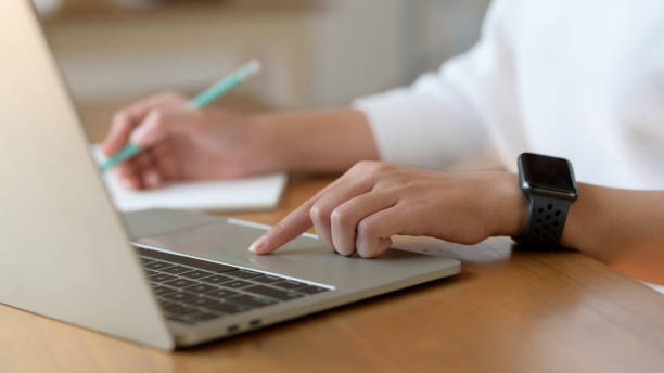 istock Close up view of college girl working on laptop while writing on notebook 1207433580