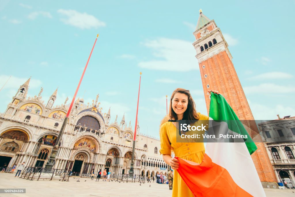 woman with italian flag on venice main square. saint marks basilica on background woman with italian flag on venice main square. saint marks basilica on background. summer vacation Italian Flag Stock Photo