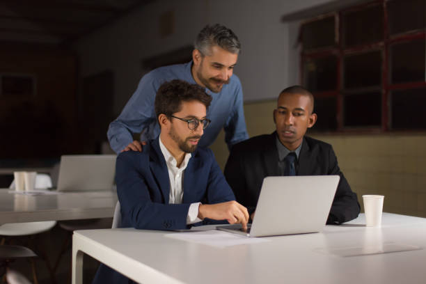 istock Three smiling handsome young businessmen looking at laptop 1207434631