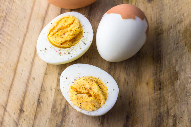 Boiled  eggs on wooden board with pepper flakes Boiled chicken eggs on wooden board with pepper flakes boiled egg photos stock pictures, royalty-free photos & images