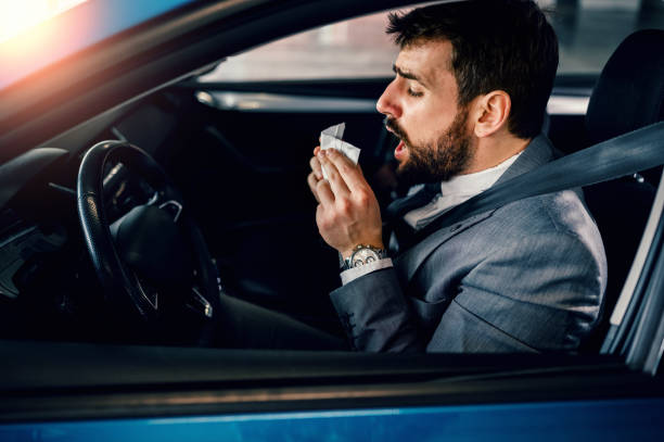 istock Businessman blowing his nose inside the car 1207437937