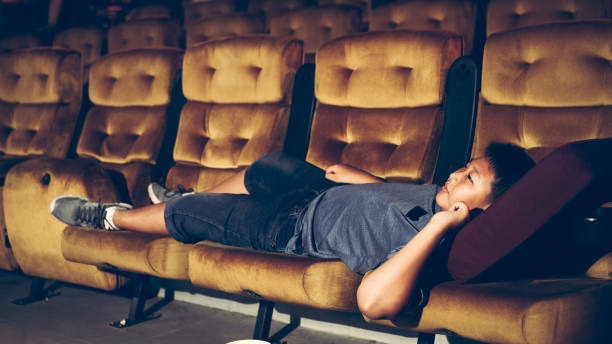 istock A boy laying down on armchair in cinema. 1207438086