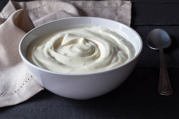 istock Greek yogurt in a white bowl on a rustic black wooden table. 1207438791