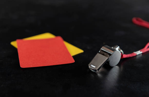 Whistle with red and yellow soccer card on the black background.