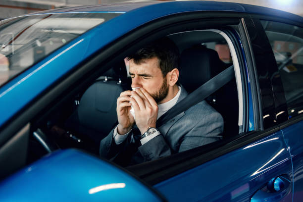 istock Businessman blowing his nose inside the car 1207441630