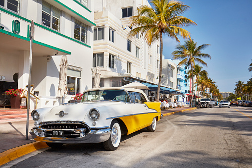 Miami, USA - February 06, 2020: Yellow Classic Oldsmobile car park at Ocean Drive in a sunny day, Miami, USA