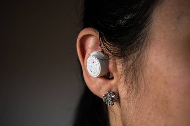 White wireless headphone in woman ear with four leaf clover earring White wireless headphone in woman ear with four leaf clover earring translation earbuds that actually work stock pictures, royalty-free photos & images