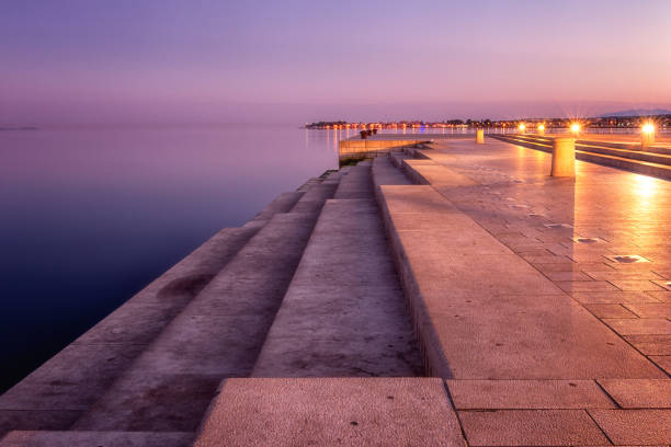 Sea organ (morske orgulje) in Zadar at sunrise, architectural landmark, Croatia. Scenic landscape Sea organ (morske orgulje) in Zadar at sunrise, architectural landmark, Croatia. Scenic landscape of popular tourist attraction, outdoor travel background croatian culture photos stock pictures, royalty-free photos & images