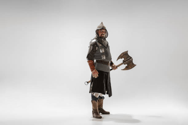 Brave armored knight with professional weapon fighting isolated on white studio background. Historical reconstruction of native fight of warriors. Concept of history, hobby, antique military art.