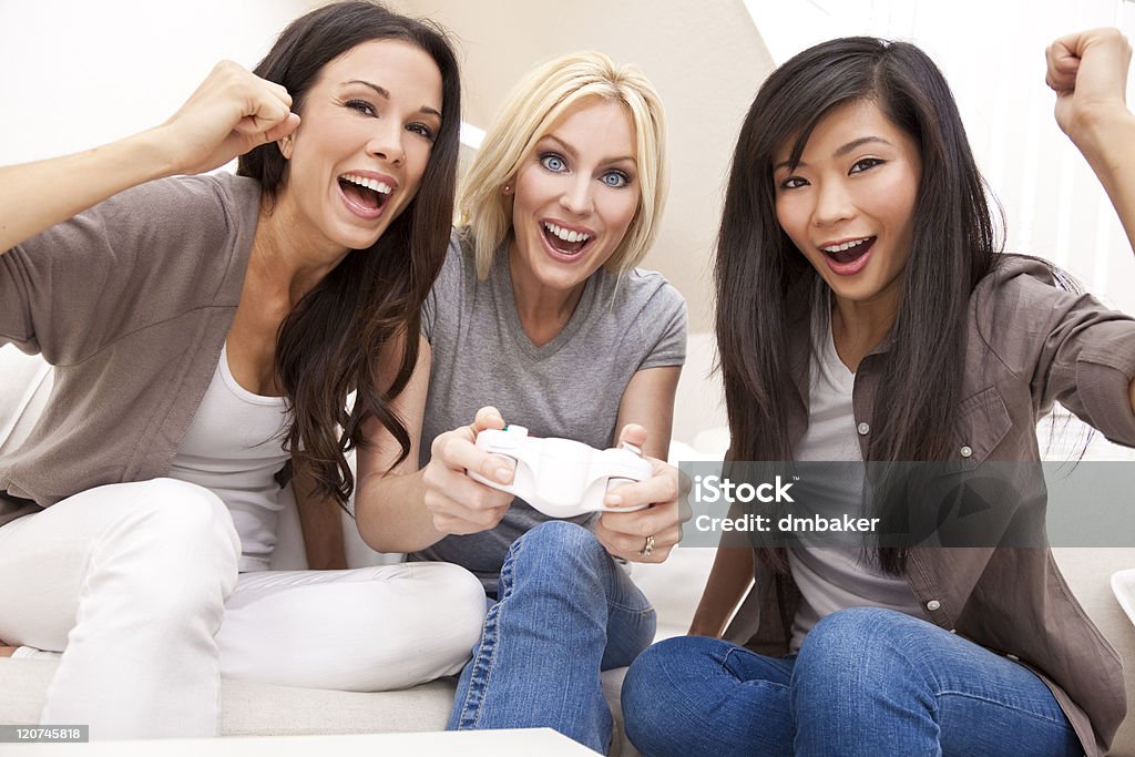 Три красивых женщин друзей играет видео игры на дому - Стоковые фото Женщины роялти-фри