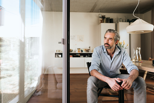pensive  bearded business man sitting on chair looking out of the window