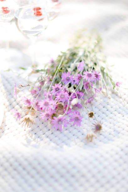 istock Violet bouquet of daisies lying on white blanket 1207460125
