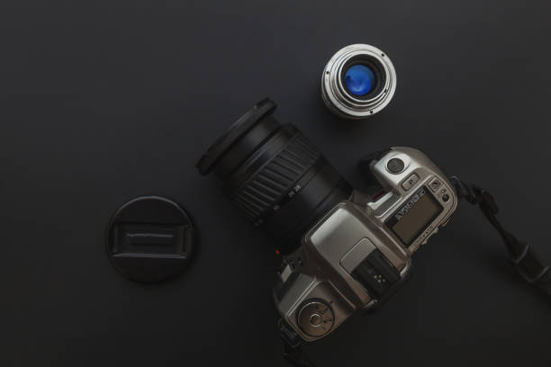 istock Photographer workplace with dslr camera system and lens on dark black table background. Hobby travel photography concept. Flat lay top view copy space 1207460570