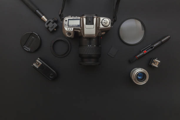 istock Photographer workplace with dslr camera system, camera cleaning kit, lens and camera accessory on dark black table background. Hobby travel photography concept. Flat lay top view copy space 1207460575